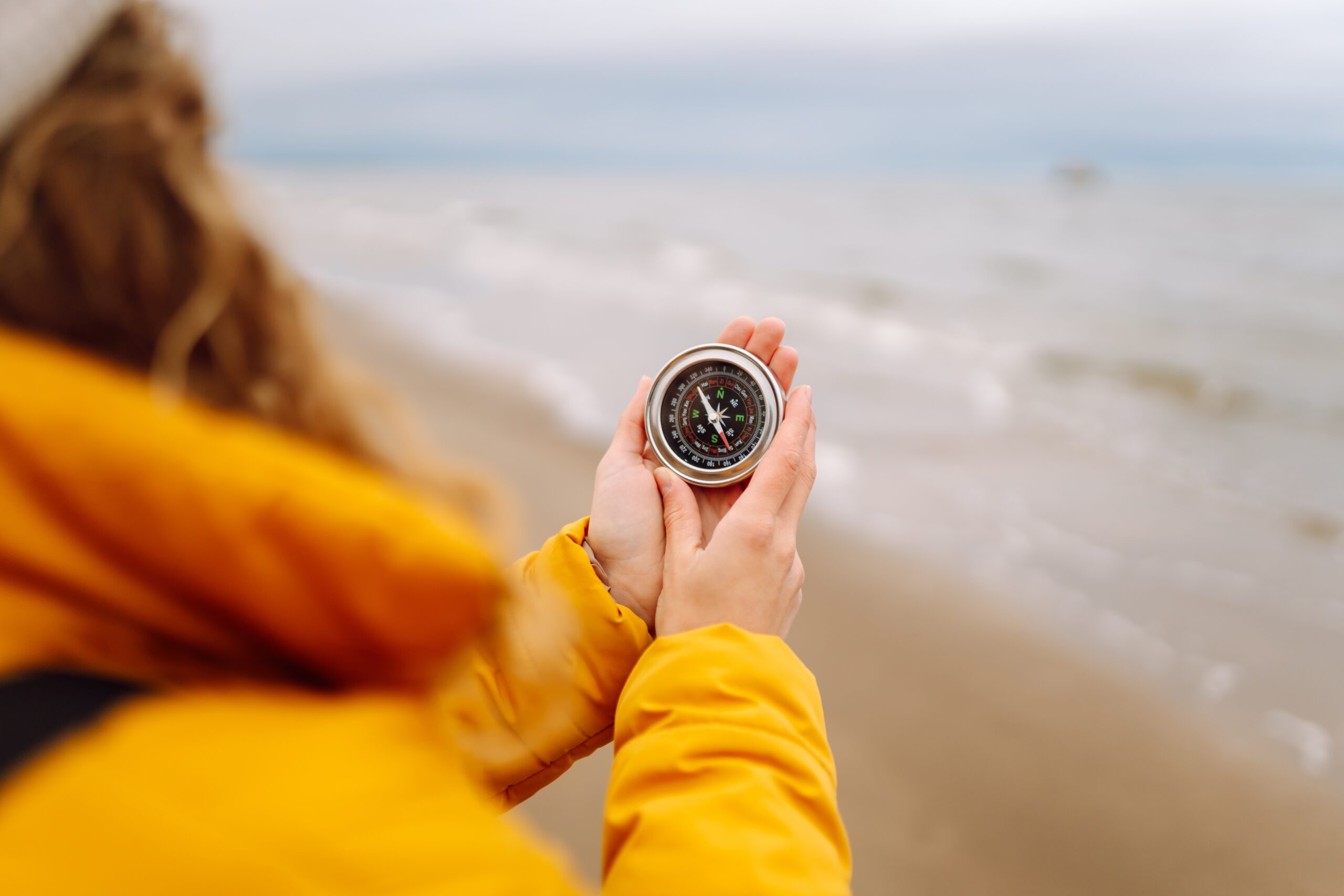 person holding compass at beach
